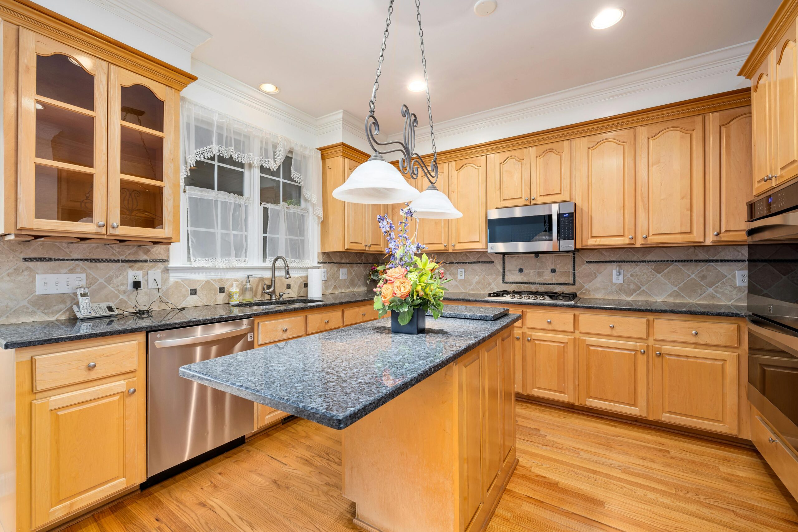 Spacious minimalist kitchen featuring wooden cabinets, marble countertops, and modern appliances.